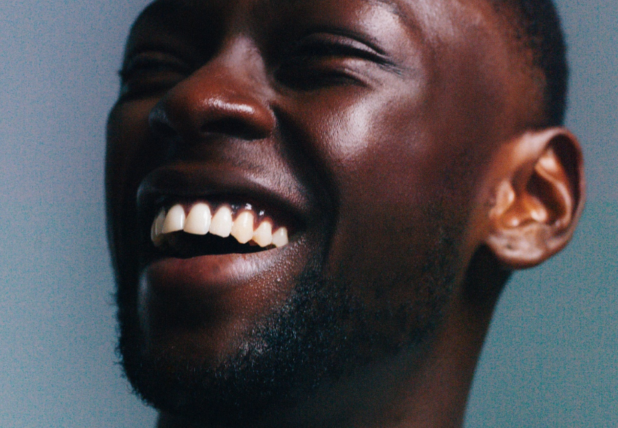 Man smiles while looking up to the left. Film grain over photo.