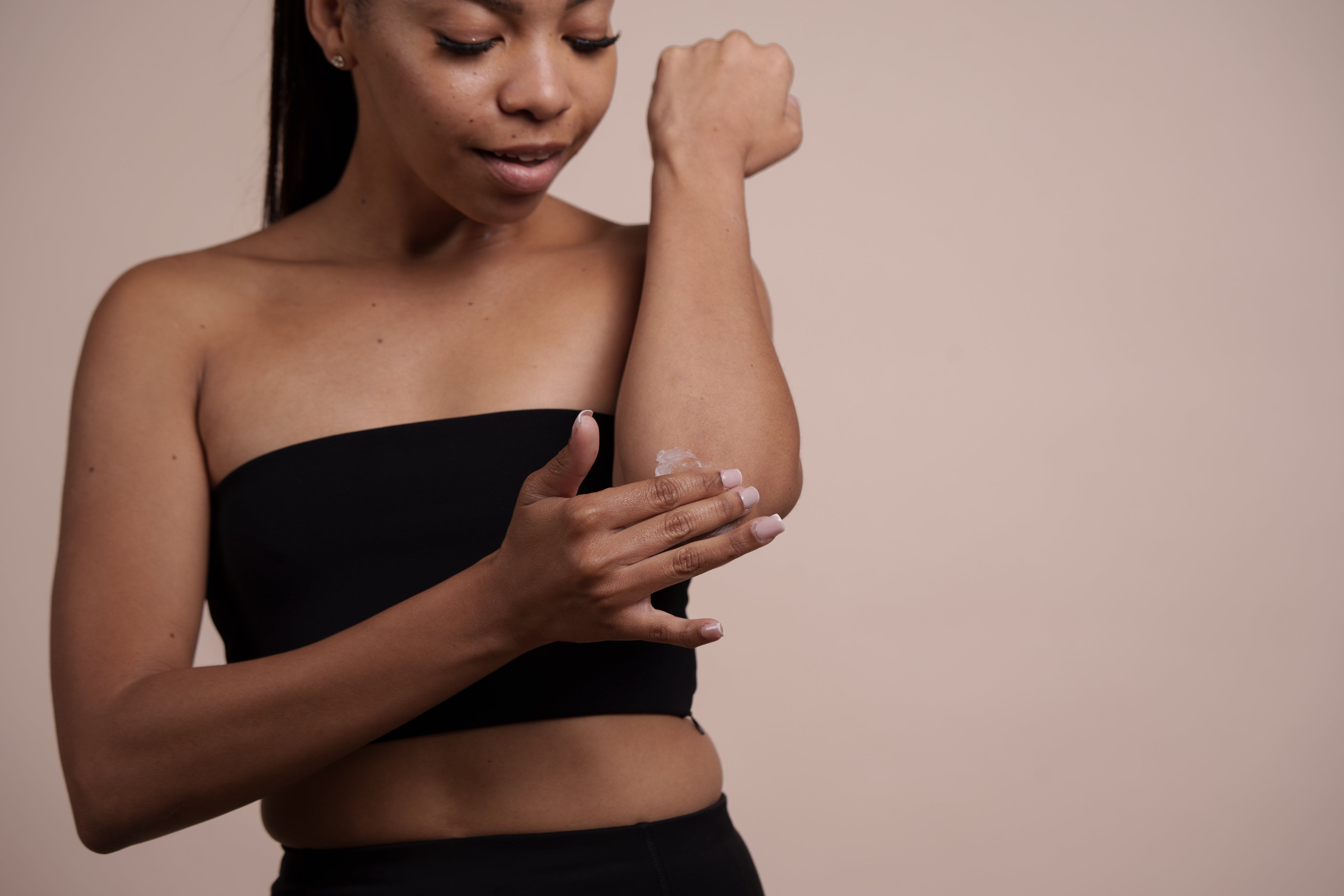 A woman carefully applies cream to her arm.